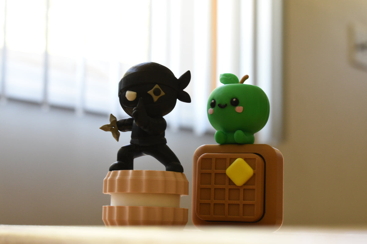 Layerplay Monomoodz Shurikid figure displayed beside a kawaii green apple character, CookieClick, and WaffleClick on a white background.