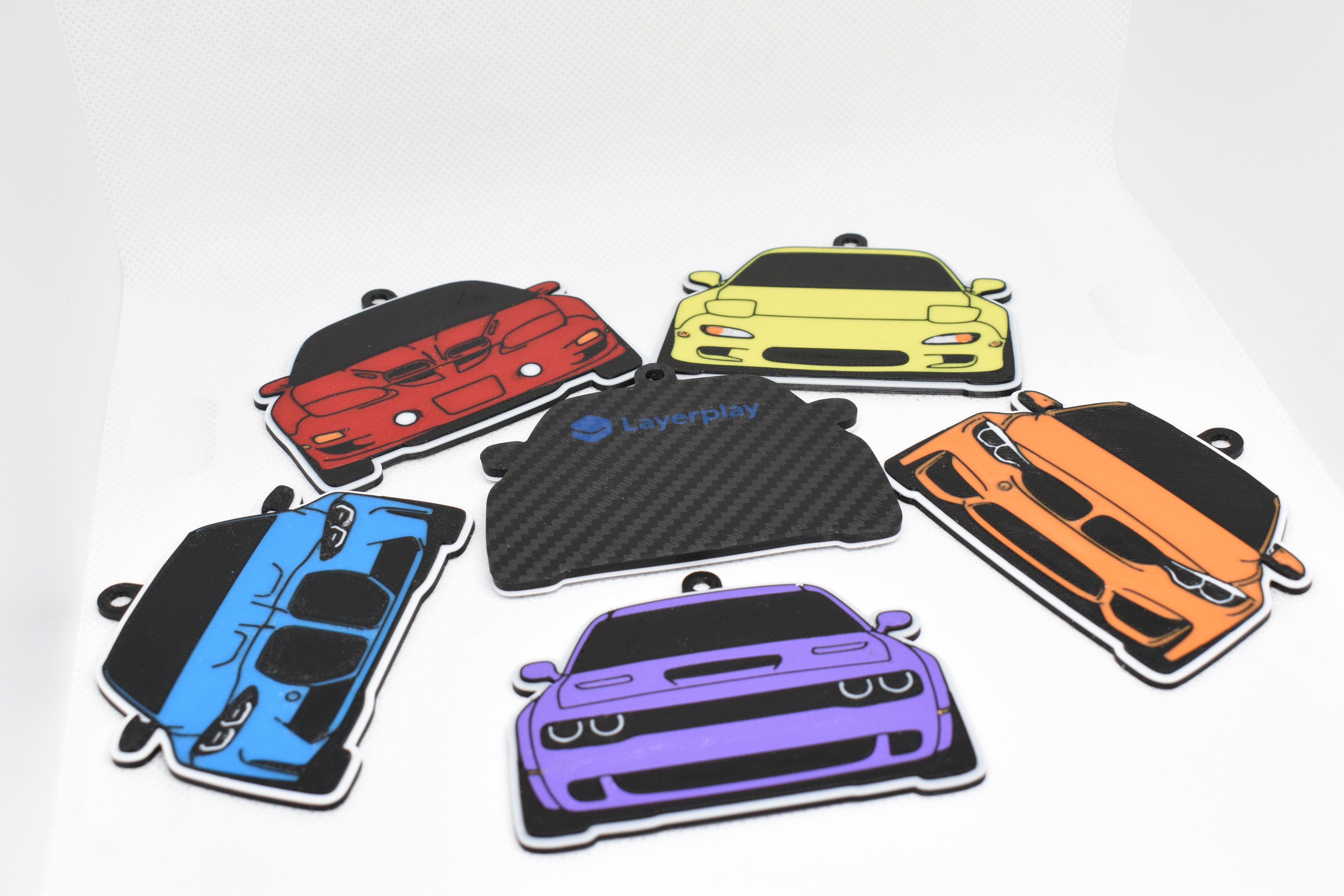 Pocket Motors car keychains arranged in a semicircle on a white background, featuring colorful JDM and muscle‑inspired designs.