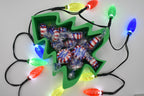 Overhead view of the green Layertreat FestiveTree 3D printed candy dish filled with wrapped peppermint candies, surrounded by glowing colorful Christmas lights.