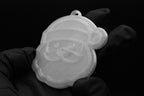 Handheld view of a 3D printed translucent clear Santa Claus Christmas tree ornament showing detailed facial features, hat, and beard against a dark background.