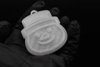 Handheld view of a 3D printed clear translucent snowman Christmas ornament with top hat detail against a dark background.