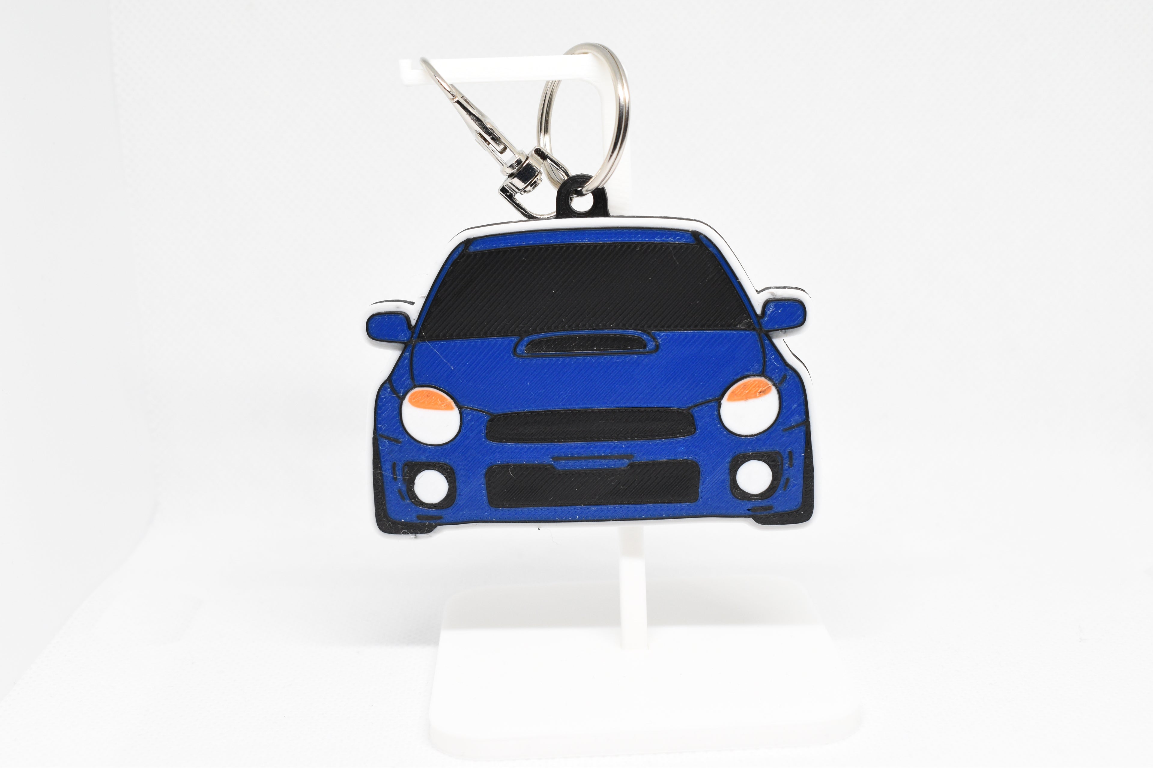 Blue Bugeye WRX keychain displayed on a white stand with metal ring and clip.