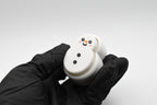 A gloved hand holding the FrostyClick snowman fidget clicker at an angle, highlighting its textured 3D printed body and mechanical switch button height.