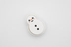 Top-down flat lay view of the FrostyClick 3D printed snowman mechanical switch fidget clicker with a smiling face, orange nose, rosy cheeks, and black coal buttons on a white background.