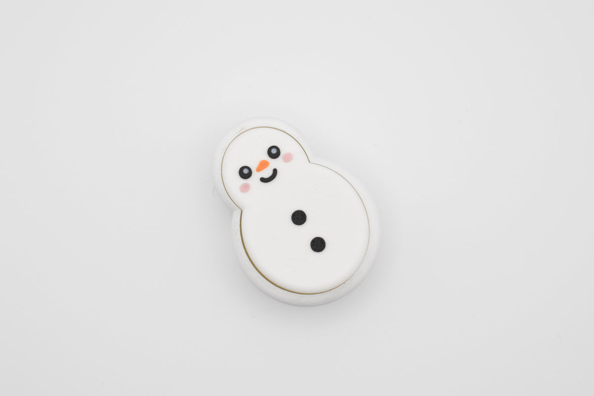 Top-down flat lay view of the FrostyClick 3D printed snowman mechanical switch fidget clicker with a smiling face, orange nose, rosy cheeks, and black coal buttons on a white background.