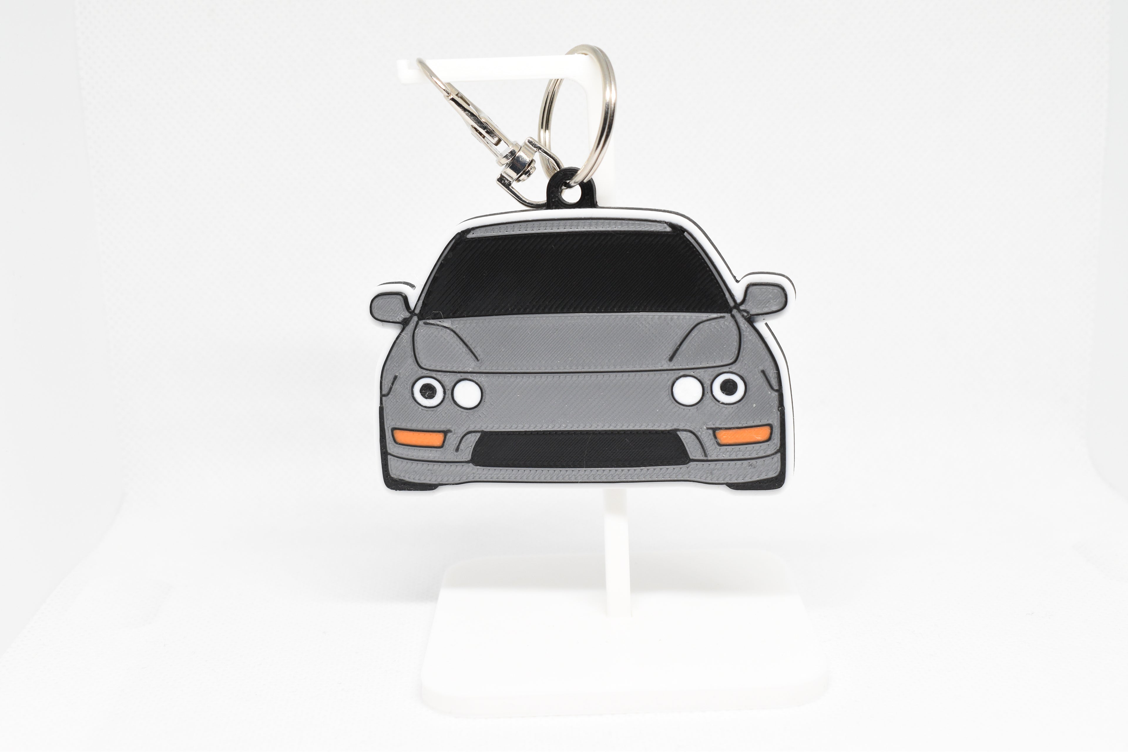 Gray Integra keychain displayed on a white stand with metal ring and clip.