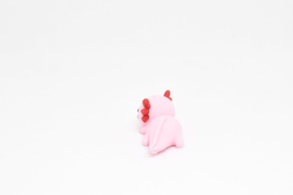 Low angle view of cute 3D printed kawaii axolotl desk toy figure resting on a white background by LayerPlay