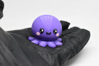 Hand in black glove holding cute 3D printed kawaii octopus desk toy figure close up by LayerPlay