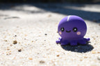 3D printed kawaii octopus desk toy figurine resting outdoors on beach sand by LayerPlay