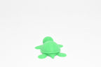 Low angle view of cute 3D printed kawaii sea turtle desk toy figure resting on a white background by LayerPlay