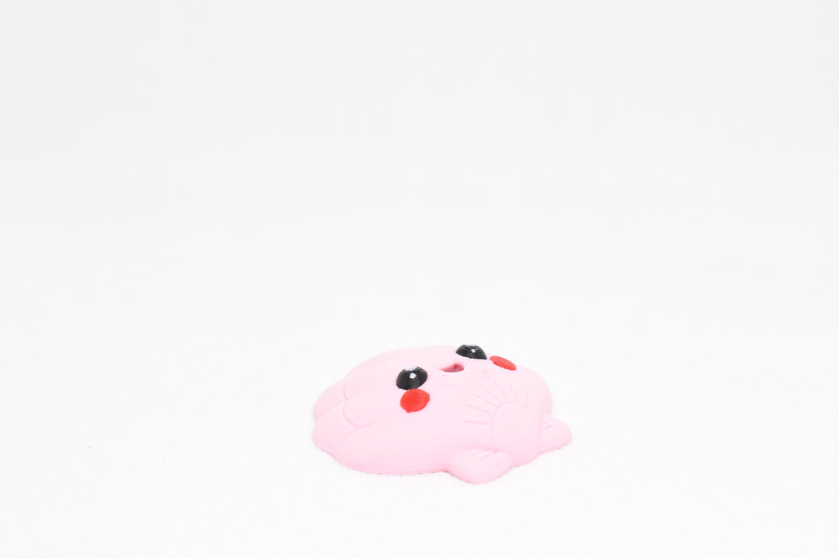 Low angle view of cute 3D printed kawaii seashell desk toy figure resting on a white background by LayerPlay