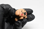 Hand in black glove holding cute 3D printed brown kawaii sleeping puppy desk toy figurine close up by LayerPlay