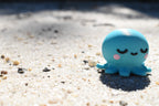 3D printed kawaii sleeping octopus desk toy figurine resting outdoors on beach sand by LayerPlay