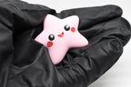 Hand in black glove holding cute 3D printed pink kawaii starfish desk toy figure close up by LayerPlay