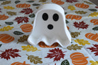 3D printed white ghost candy dish displayed upright on a fall patterned tablecloth with leaf and pumpkin print by LayerPlay Layertreat