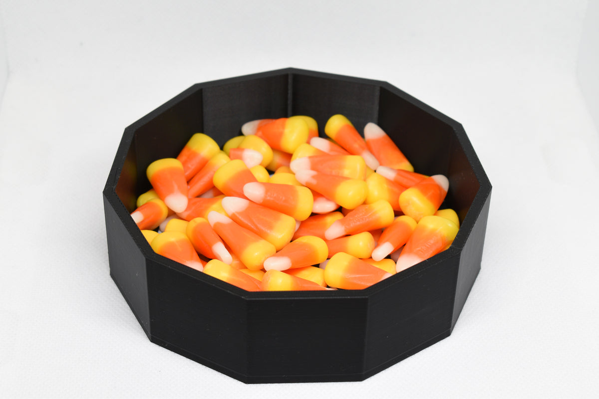 Angled studio view of 3D printed black spider web candy dish filled with candy corn for Halloween decor by LayerPlay Layertreat