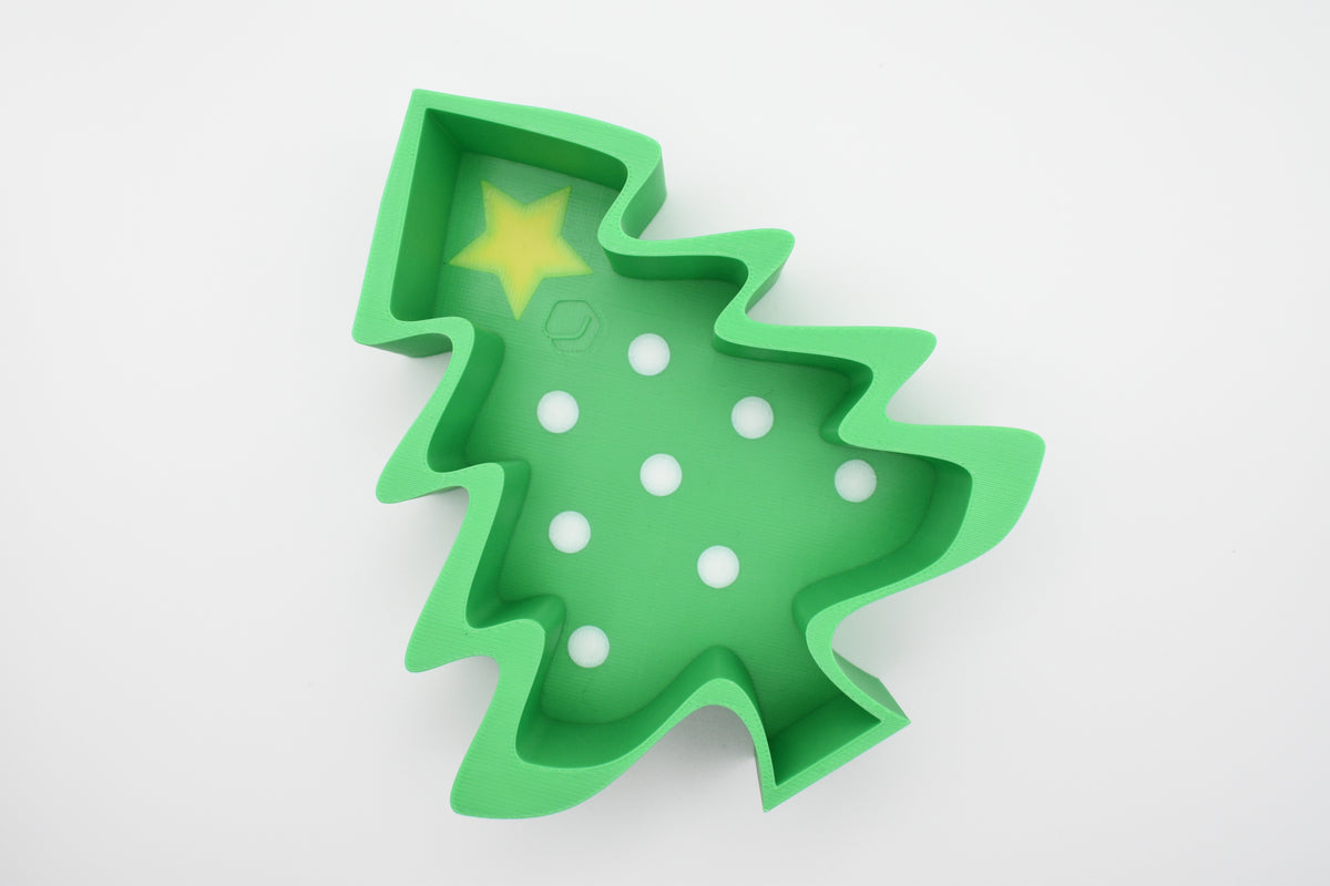 Top-down flat lay of the Layertreat FestiveTree 3D printed green Christmas tree candy dish featuring a yellow star topper and white polka dot accents on a clean white background.