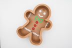 Top-down flat lay view of the Layertreat GingerBowl, a 3D printed gingerbread man candy dish featuring a green bow tie, red buttons, white icing trim, and a smiling face on a white background.
