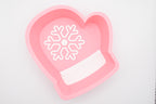 Top-down view of the Layertreat MittenBowl, a pastel pink 3D printed winter mitten candy dish featuring a white snowflake design and white cuff accent on a clean white background.