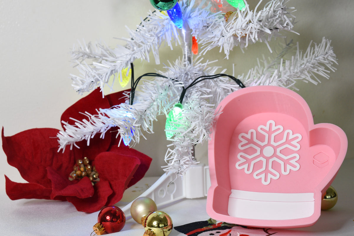 Layertreat MittenBowl pink winter mitten candy dish with white snowflake accent displayed under a lit white Christmas tree with holiday decor.