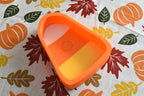 3D printed tri-color candy corn dish displayed on a fall patterned tablecloth with leaf and pumpkin print by LayerPlay Layertreat