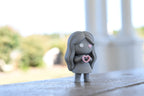 3D printed grey monomoodz corra desk figure standing outdoors on a railing with blurred garden background by LayerPlay