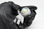 Hand in black glove holding cute grey 3D printed monomoodz drift hoodie desk figure close up by LayerPlay