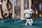 3D printed grey monomoodz erix desk figure in fighting pose standing outdoors on a green surface with blurred background by LayerPlay