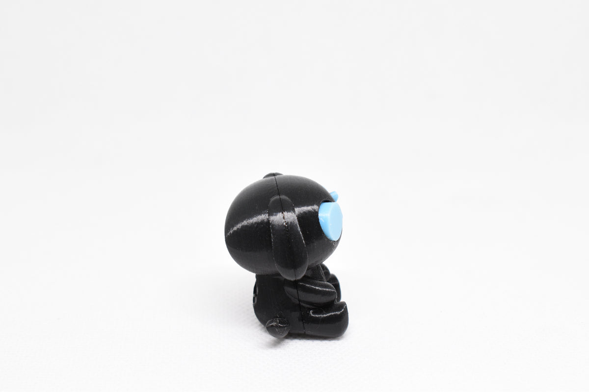 Side profile view showing black body, floppy dog ears, and glow in the dark eye detail of 3D printed monomoodz glyphie dog desk figure by LayerPlay