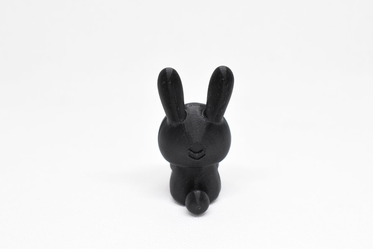 Rear view showing long rabbit ears and fluffy tail of black 3D printed monomoodz glow in the dark nixie bunny figure by LayerPlay