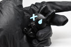 Hand in black glove holding 3D printed black monomoodz glow in the dark nixie bunny figure with white X and glow circle eyes close up by LayerPlay