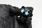 Hand in black glove holding 3D printed black monomoodz glow in the dark twinkle bear figure with blue star eyes close up by LayerPlay