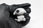 Hand in black glove holding cute 3D printed grey monomoodz glyphie dog desk figure close up by LayerPlay 