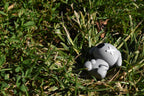 3D printed grey monomoodz glyphie dog desk figure reclining outdoors in green grass under sunlight by LayerPlay