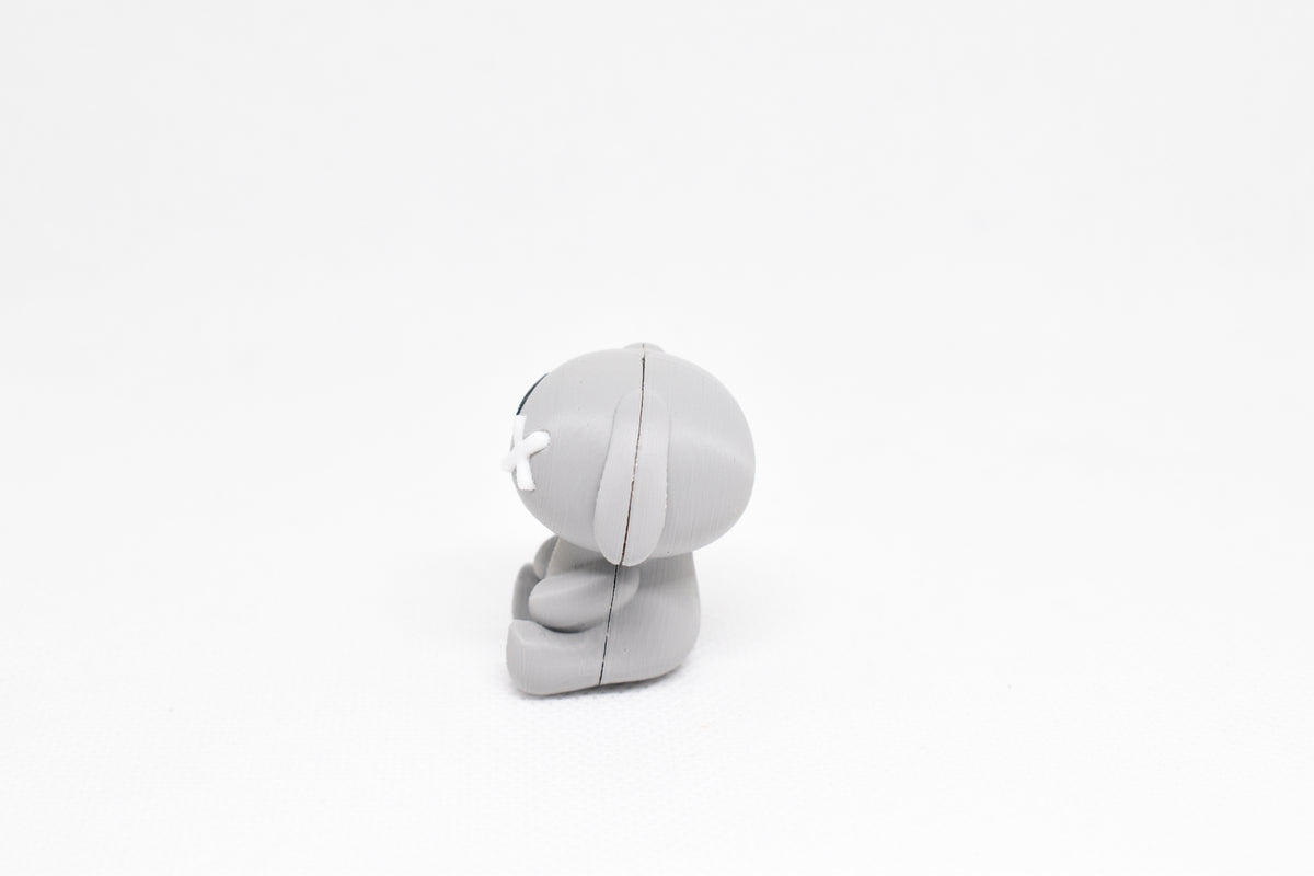 Side profile view showing floppy ear and white X eye detail of 3D printed monomoodz glyphie dog desk figure by LayerPlay