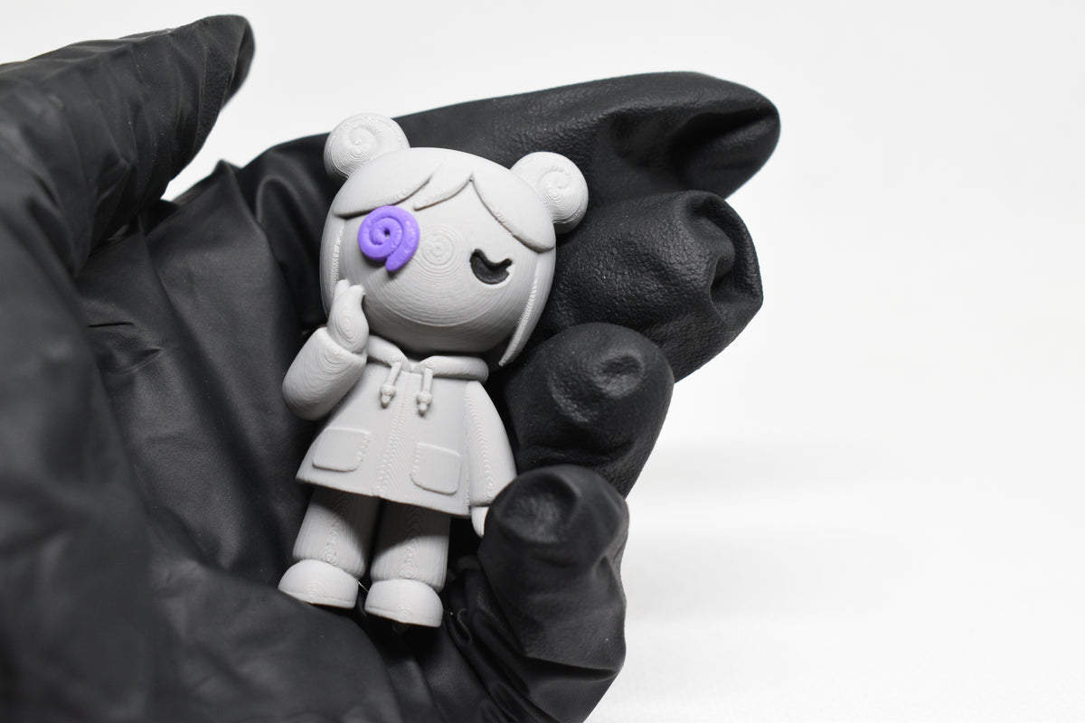 Hand in black glove holding cute grey 3D printed monomoodz kiri desk figurine close up by LayerPlay