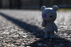 3D printed grey monomoodz kiri desk figure standing outdoors on asphalt pavement with dramatic lighting by LayerPlay