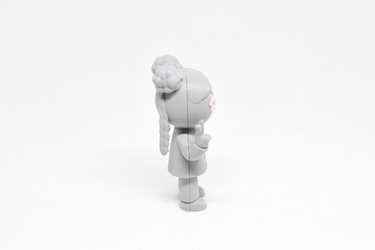 Side profile view showing braided hair pigtails, space bun hairstyle, and peace hand pose of 3D printed monomoodz lunella desk figure by LayerPlay