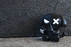 3D printed black monomoodz ninja glyphie dog desk figure sitting outdoors against a dark textured wall with shuriken in hand by LayerPlay