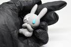 Hand in black glove holding cute 3D printed grey monomoodz nixie bunny desk figure close up by LayerPlay