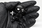 Hand in black glove holding 3D printed black monomoodz shurikid ninja desk figure close up by LayerPlay
