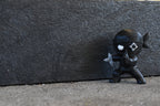 3D printed black monomoodz shurikid ninja desk figure posing stealthily outdoors against a textured dark background by LayerPlay