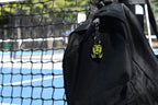 Pixelated 6 7 emoji keychain clipped to a black backpack zipper outdoors near a tennis court by LayerPlay