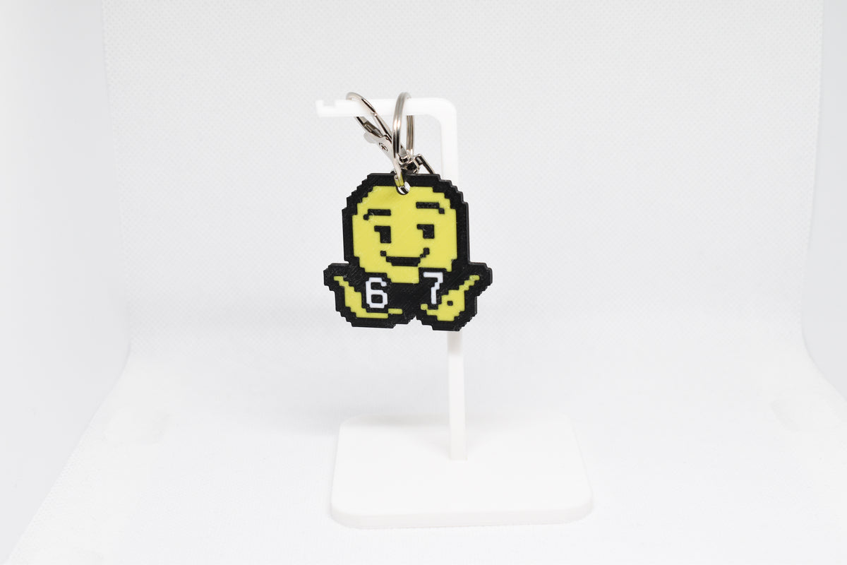3D printed retro pixelated 6 7 emoji keychain hanging on a white display stand by LayerPlay