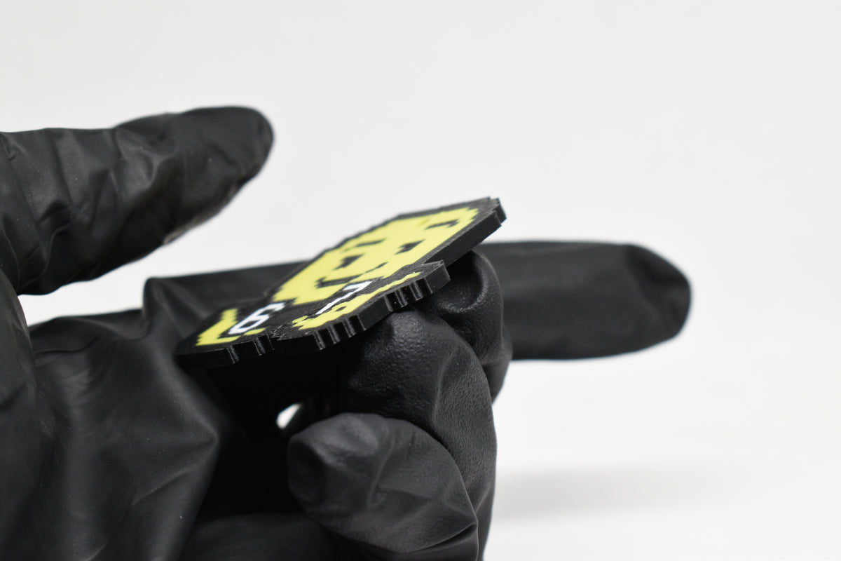 Side angle view showing 3D layered pixel detail and thickness of pixelated 6 7 emoji keychain by LayerPlay