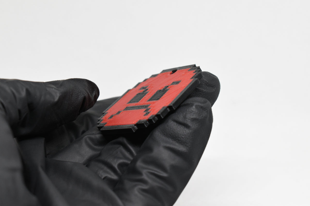 Side angle view showing 3D layered pixel detail and thickness of red pixelated angry emoji keychain by LayerPlay