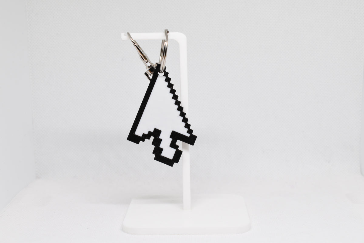 3D printed pixelated arrow mouse cursor keychain hanging on a white display stand by LayerPlay