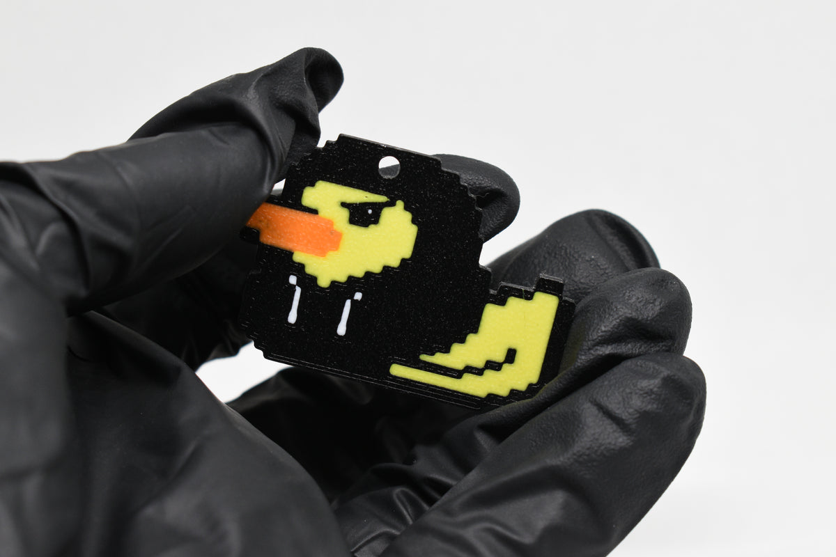 Hand in black glove holding 3D printed retro Hoodie Duck pixel rubber duck keychain front view detail by LayerPlay