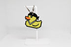 3D printed retro Lil Quack pixel rubber duck keychain hanging on a white display stand by LayerPlay