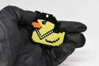 Hand in black glove holding 3D printed retro Lil Quack pixel rubber duck keychain front view detail by LayerPlay